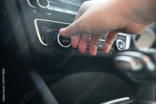 Close-up of hand using temperature control knob on car dashboard from driver side