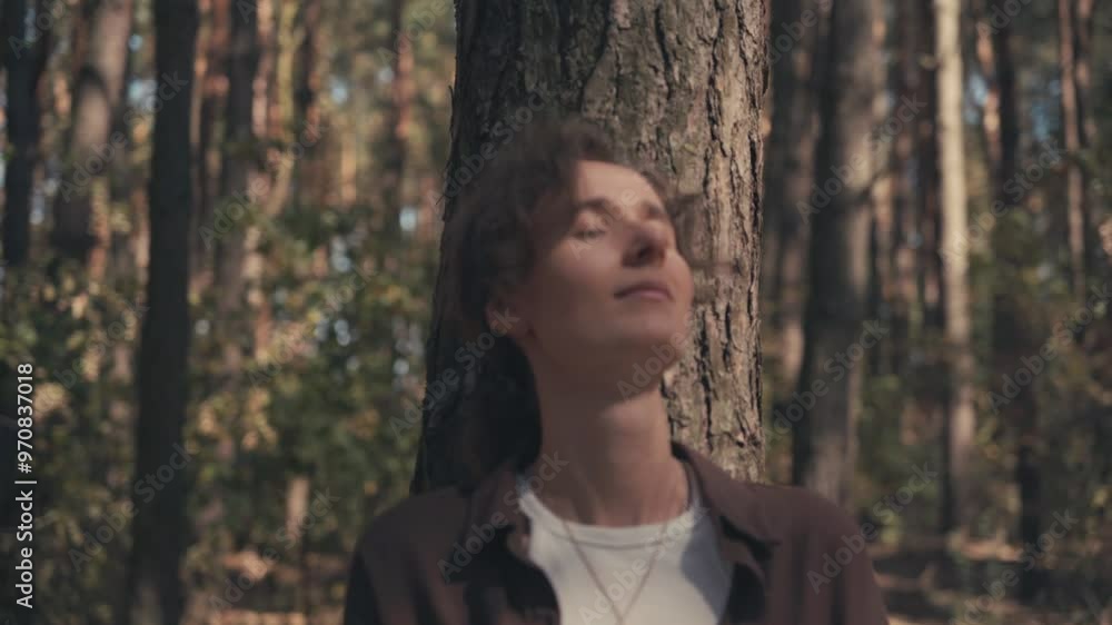 A girl of Slavic appearance in an autumn pine forest, leaning against a pine tree, hair in a bun, sun rays falling on her face, eyes closed, putting her hands behind her head, smiling, close-up A girl of Slavic appearance in an autumn pine forest, leaning against a pine tree, hair in a bun, sun rays falling on her face, eyes closed, putting her hands behind her head, smiling, close-up