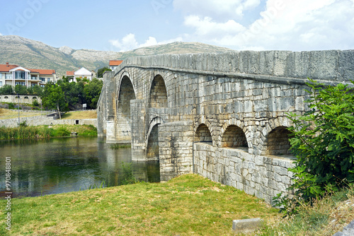 Arslanagic (Perovic) Bridge - view from the Trebišnjica bank on a sunny summer day. Ottoman architectural heritage in Trebinje, Bosnia and Herzegovina: a monumental stone bridge with arches.