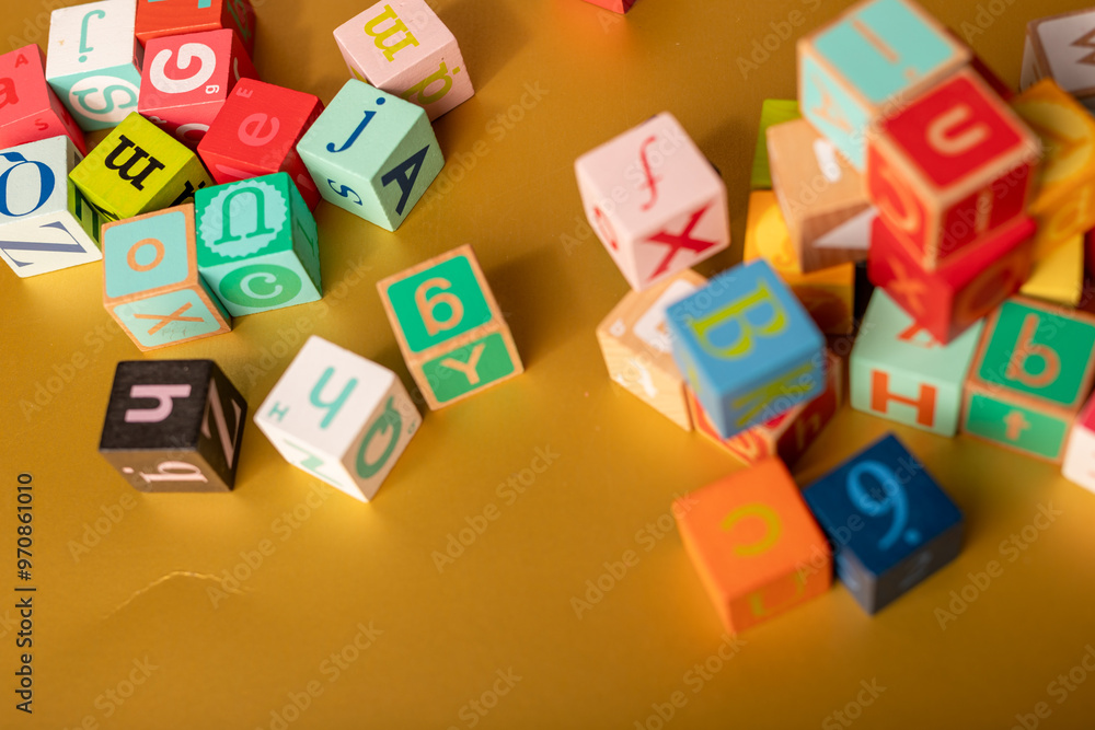 A colorful alphabet blocks scattered on a gold surface Learn and play A colorful alphabet blocks scattered on a gold surface Learn and play