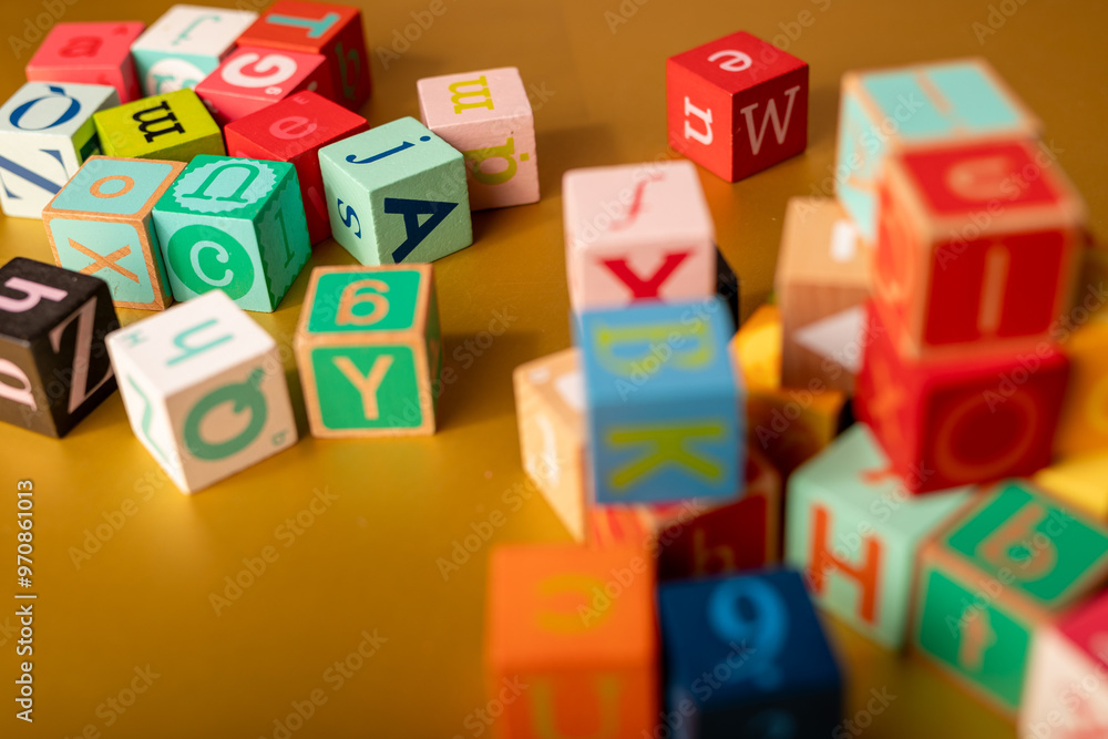 Obraz premium A colorful alphabet blocks scattered across a golden surface