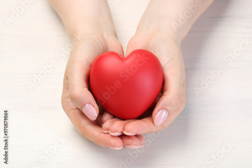 Woman with red decorative heart at white wooden table, closeup