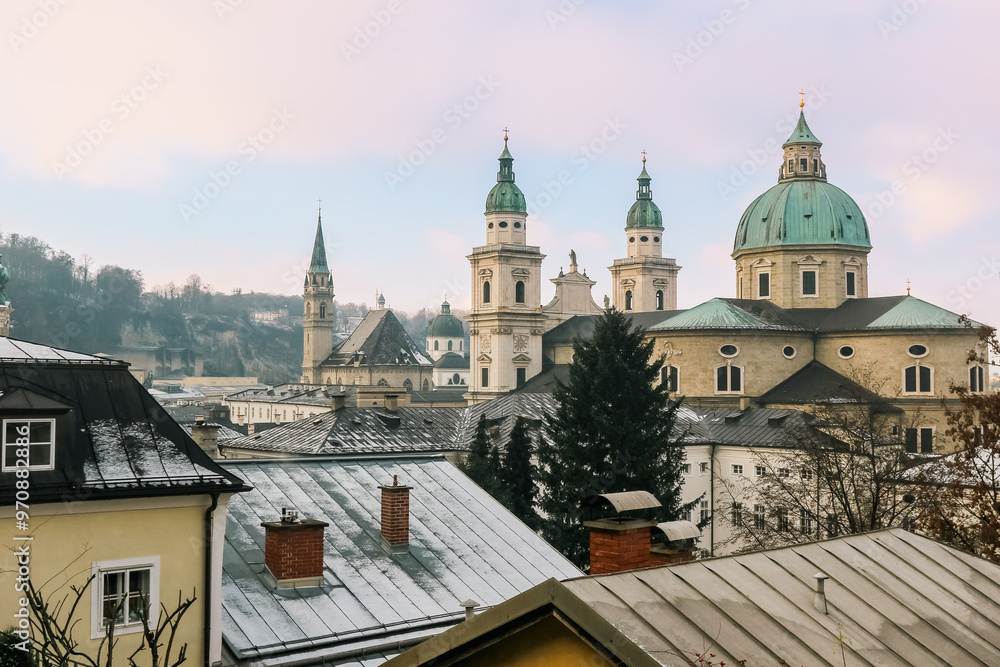 Naklejka premium Winter views of Salzburg showcasing historic architecture and snow-dusted rooftops against a pastel sky