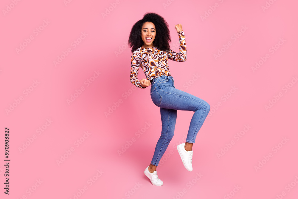 Full length photo of lucky pretty lady dressed print shirt rising fists empty space isolated pink color background Full length photo of lucky pretty lady dressed print shirt rising fists empty space isolated pink color background