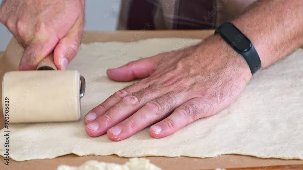 Pizza dough being rolled and pressed thin by a man on a baking sheet. Close-up on hands and dough, with a focus on homemade, healthy family cooking. Pizza dough being rolled and pressed thin by a man on a baking sheet. Close-up on hands and dough, with a focus on homemade, healthy family cooking.