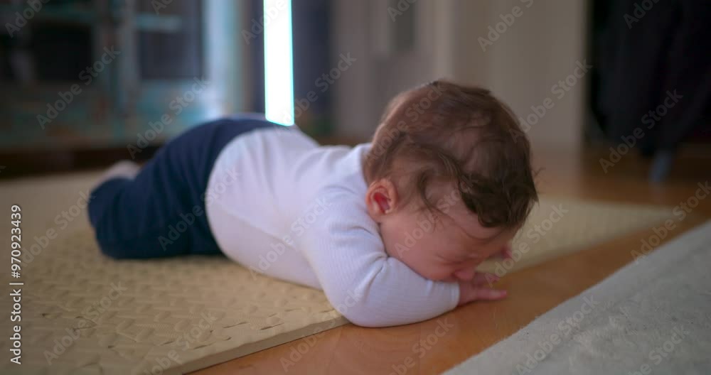 Baby lying face down on the floor, visibly upset and crying, expressing frustration and discomfort on a soft mat in a home setting, emphasizing early stages of emotional development Baby lying face down on the floor, visibly upset and crying, expressing frustration and discomfort on a soft mat in a home setting, emphasizing early stages of emotional development
