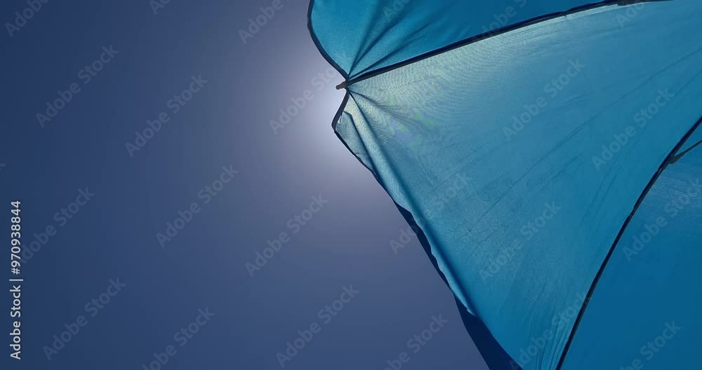 bottom view of a blue sea umbrella under a clear blue sky and sun, concept of travel, vacation and relax