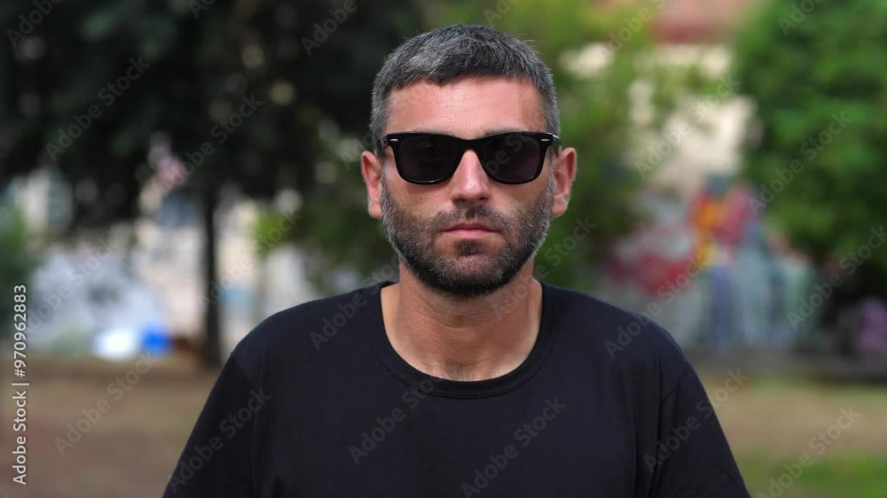 A man wearing sunglasses stares seriously into the camera, his expression stern and unyielding. The sunglasses add a touch of mystery and intensity to his gaze. A man wearing sunglasses stares seriously into the camera, his expression stern and unyielding. The sunglasses add a touch of mystery and intensity to his gaze.