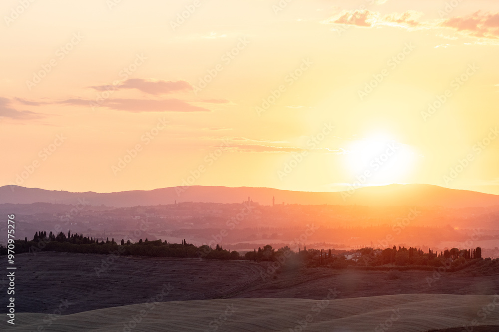 Orange and pink sunset over distant hills, with silhouettes of trees and a fading sky. The city of Siena as silhouette background. Sunset in Tuscany, romantic Orange and pink sunset over distant hills, with silhouettes of trees and a fading sky. The city of Siena as silhouette background. Sunset in Tuscany, romantic