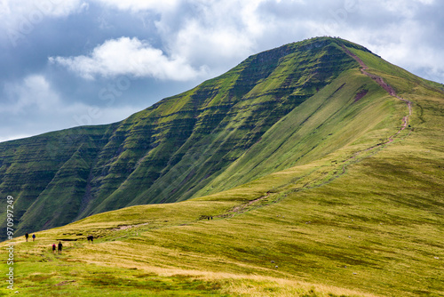 Konstfotografi Hikers ascending Pen-y-Fan in the Brecon Beacons from the Cwm Gwdi ridge on the
