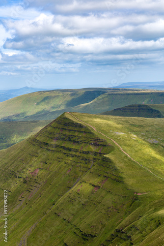 Sunshine and shadows on the summit of a green mountain top in summer photo