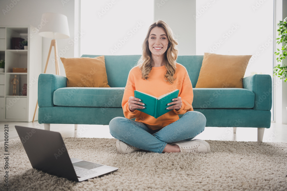 Full length photo of nice cheerful girl sit floor netbook read book dressed orange garment spend pastime spacious house indoors room Full length photo of nice cheerful girl sit floor netbook read book dressed orange garment spend pastime spacious house indoors room