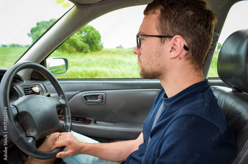 Young adult man driving the car and looking at road Young adult man driving the car and looking at road