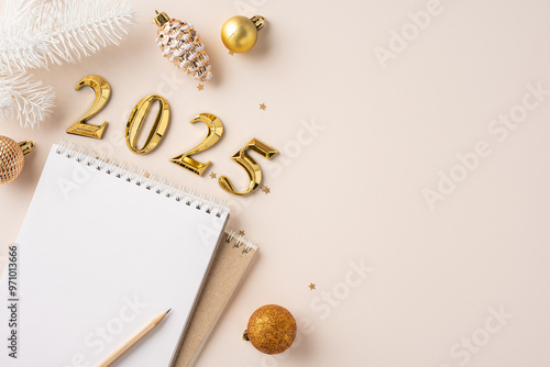 A blank notebook with a pencil placed alongside golden 2025 decorations and ornaments, symbolizing new year resolutions and planning photo