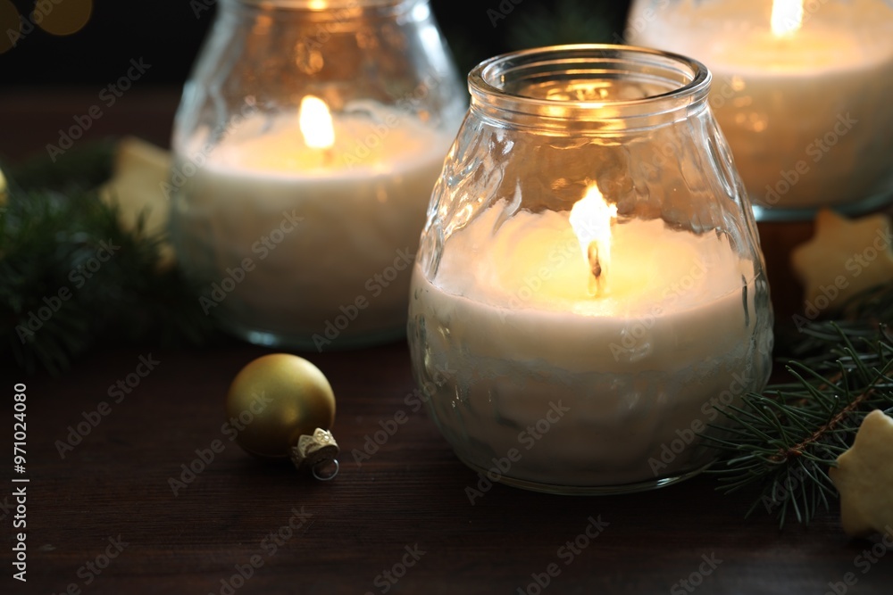 Burning candles, baubles and fir tree branches on wooden table, closeup Burning candles, baubles and fir tree branches on wooden table, closeup