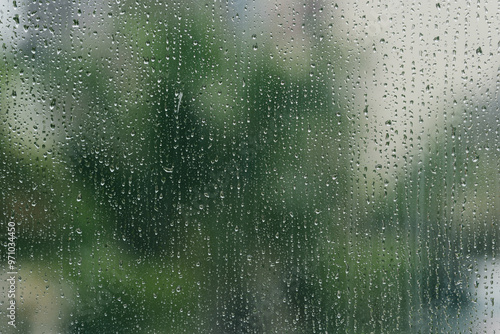 Rain-Kissed Windowpane: A serene view of nature through a rain-streaked window, with water droplets creating an abstract pattern against a blurred green backdrop. 