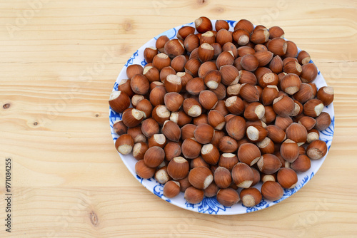 Hazelnuts in shell on a plate, wooden background  photo