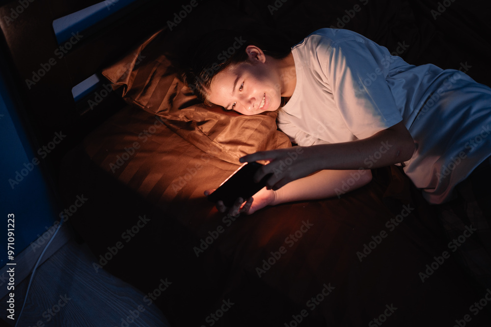 Portrait teenager girl lying on bed, at night, using phone watching movie, playing online games in her bedroom Portrait teenager girl lying on bed, at night, using phone watching movie, playing online games in her bedroom
