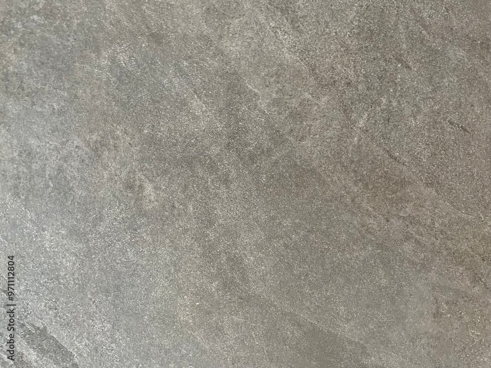 Fototapeta premium Marble Tile texture closeup as an abstract background. Natural Honed stone slab. Details of matte ceramic wall or floor. Gray surface with satin finish and a pattern of random irregular white spots.