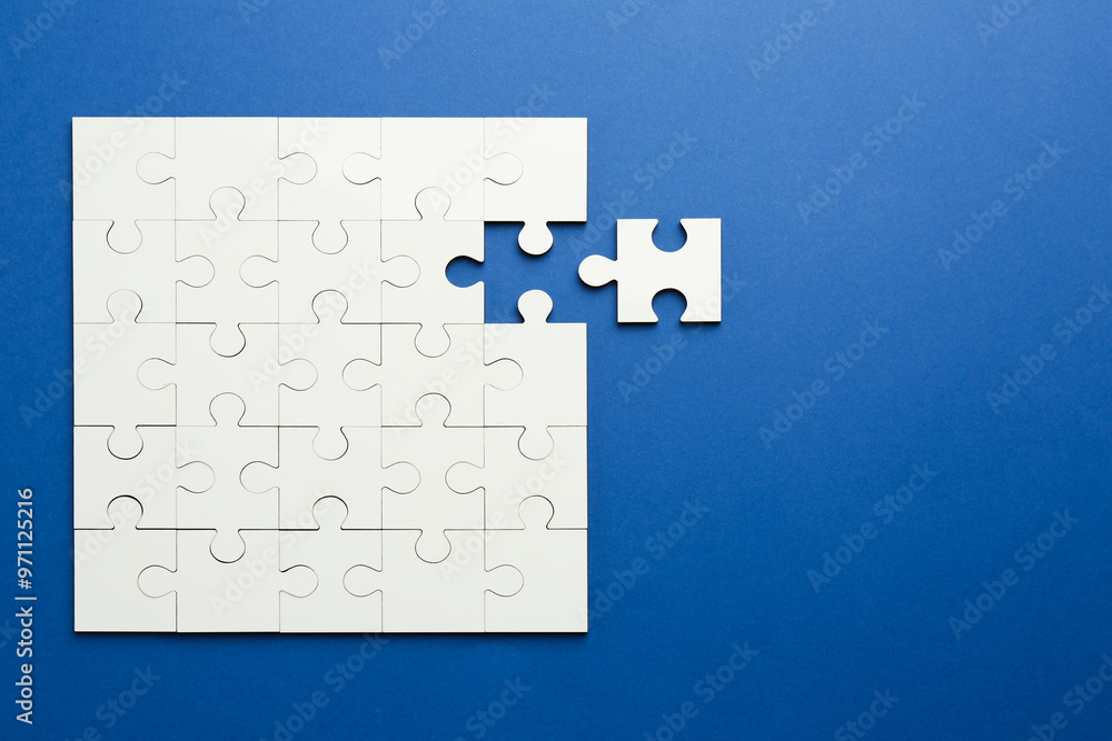 Fototapeta premium White puzzle pieces on blue background, top view