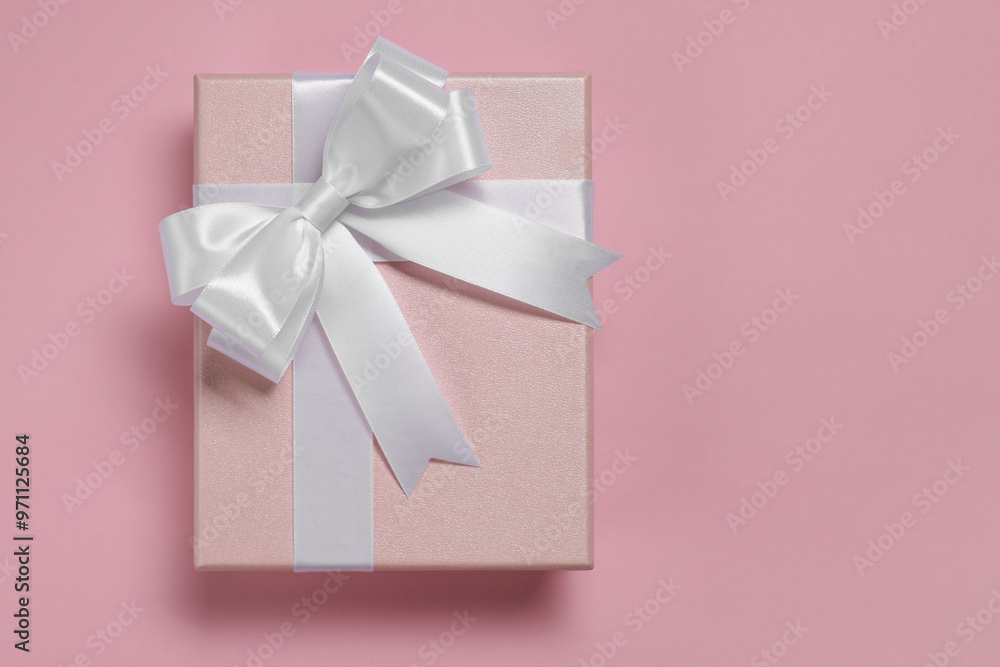 Gift box with bow on dusty pink background, top view Gift box with bow on dusty pink background, top view