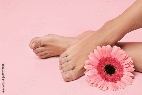 Woman with smooth feet and flower on pink background, closeup