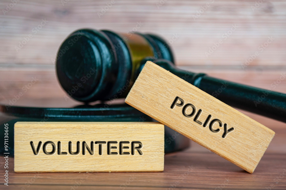 Volunteer policy text engraved on wooden blocks with gavel background. Volunteer policy concept Volunteer policy text engraved on wooden blocks with gavel background. Volunteer policy concept
