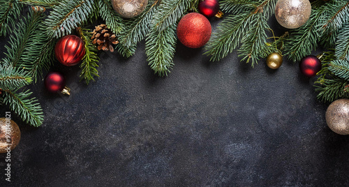 Christmas decoration background with fir branches, red tree balls and pine cones with place for copytext copyspace card. Black natral stone. 