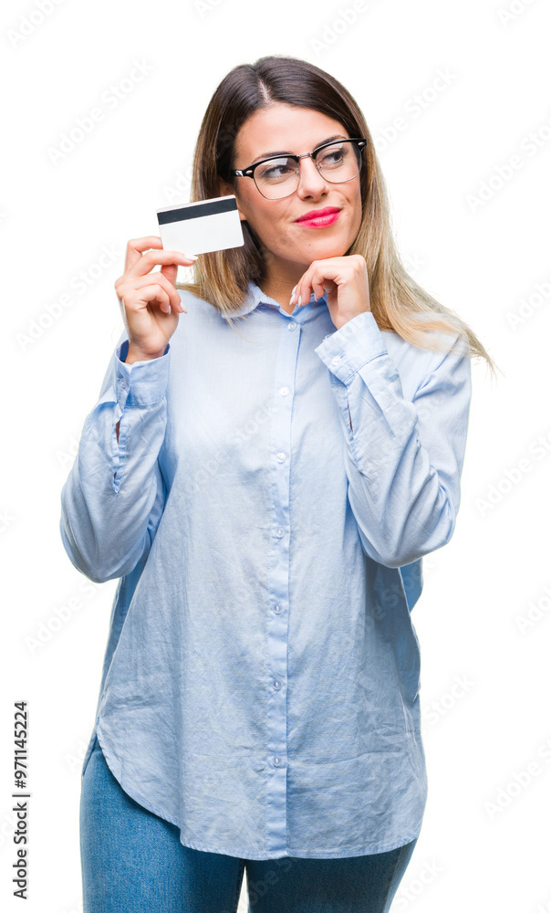 Young beautiful business woman holding credit card over isolated background serious face thinking about question, very confused idea Young beautiful business woman holding credit card over isolated background serious face thinking about question, very confused idea