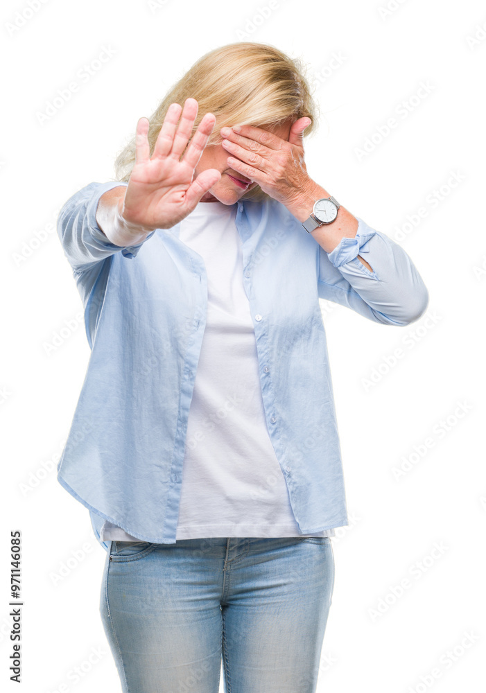 Middle age blonde woman over isolated background covering eyes with hands and doing stop gesture with sad and fear expression. Embarrassed and negative concept. Middle age blonde woman over isolated background covering eyes with hands and doing stop gesture with sad and fear expression. Embarrassed and negative concept.