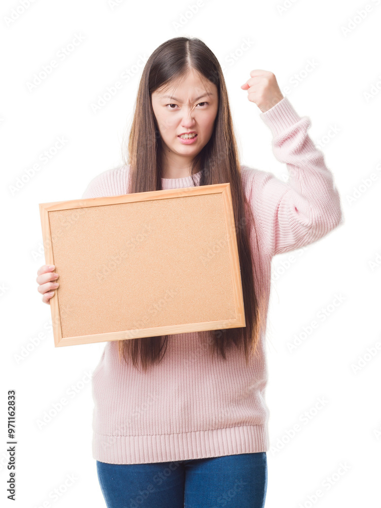 Young Chinese woman over isolated background holding corkboard annoyed and frustrated shouting with anger, crazy and yelling with raised hand, anger concept Young Chinese woman over isolated background holding corkboard annoyed and frustrated shouting with anger, crazy and yelling with raised hand, anger concept
