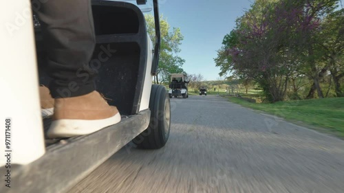 Golf players driving on sport golf carts along the road through amazing green mowed lawns, wheels of driving carts along the pavement road, sport game lovers and recreational concept