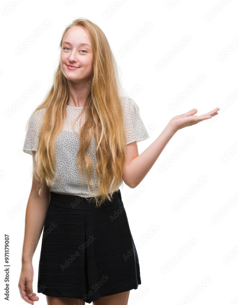 Blonde teenager woman wearing moles shirt smiling cheerful presenting and pointing with palm of hand looking at the camera. Blonde teenager woman wearing moles shirt smiling cheerful presenting and pointing with palm of hand looking at the camera.