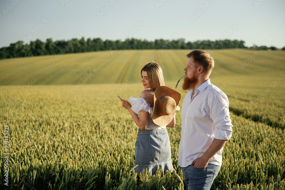 Side view, walking. Lovely couple are on the green agricultural field together Side view, walking. Lovely couple are on the green agricultural field together