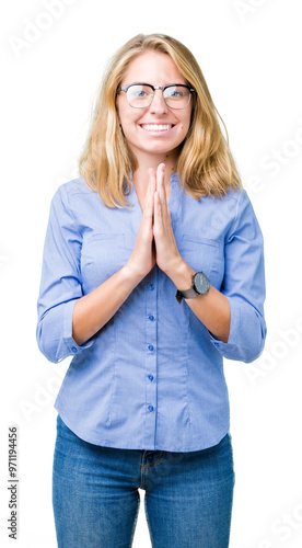 Beautiful young business woman over isolated background praying with hands together asking for forgiveness smiling confident. photo