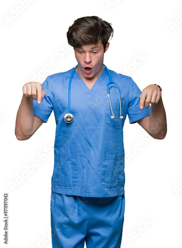 Young doctor wearing medical uniform over isolated background Pointing down with fingers showing advertisement, surprised face and open mouth