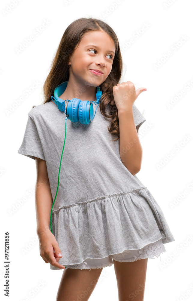 Brunette hispanic girl wearing headphones pointing and showing with thumb up to the side with happy face smiling Brunette hispanic girl wearing headphones pointing and showing with thumb up to the side with happy face smiling