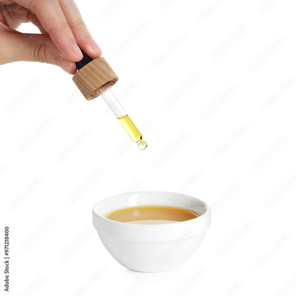 Woman dripping tincture from pipette into bowl on white background, closeup Woman dripping tincture from pipette into bowl on white background, closeup