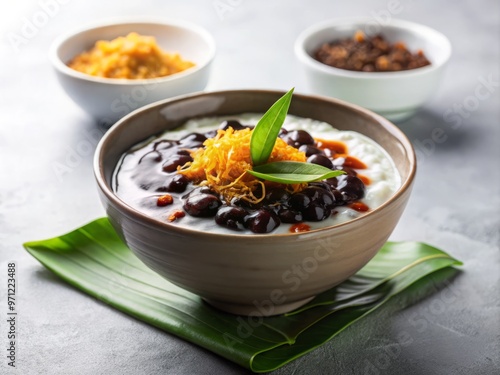 • Bubur pulut hitam, adorned with a delicate sprinkle of toasted coconut flakes and a drizzle of gula Melaka, resting on a clean, white surface, with a shallow depth of field blurring the edges