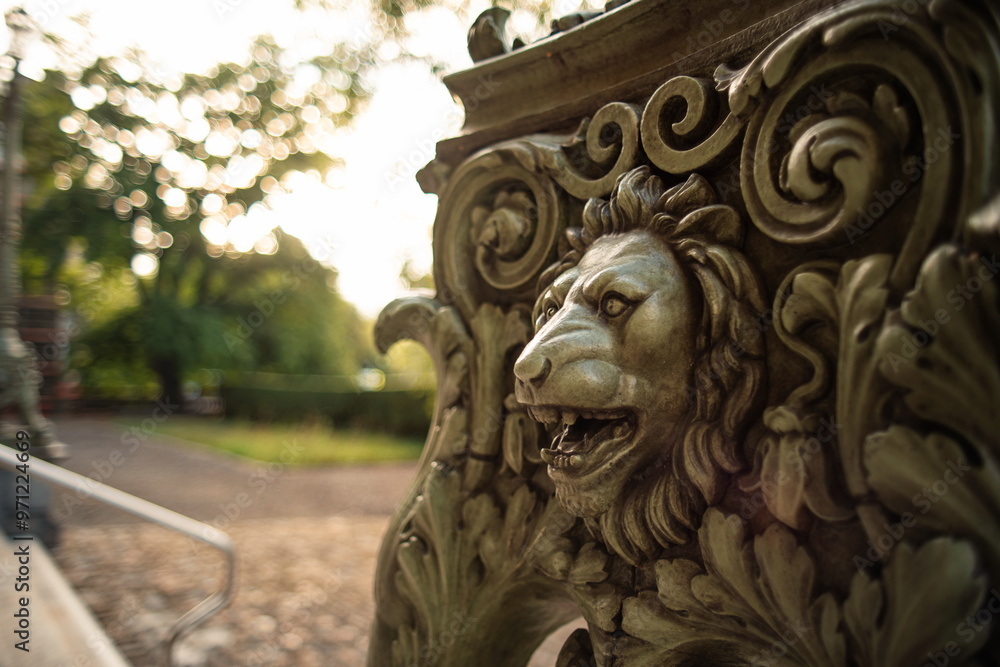 Old, metal sculpted lion head statue. Close up shot of head and mane, shallow depth of field, backlit by sunrise, no people Old, metal sculpted lion head statue. Close up shot of head and mane, shallow depth of field, backlit by sunrise, no people