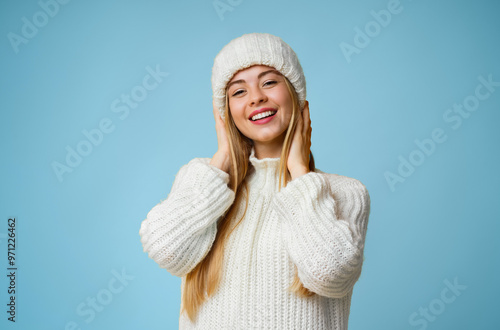 Portrait of pretty smiling girl in white knitted winter set over yellow background, copy space