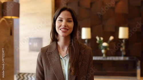 Cheerful young businesswoman standing and smiling in the company lobby