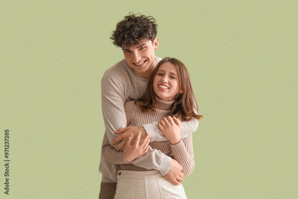 Young beautiful couple in stylish clothes hugging on green background Young beautiful couple in stylish clothes hugging on green background