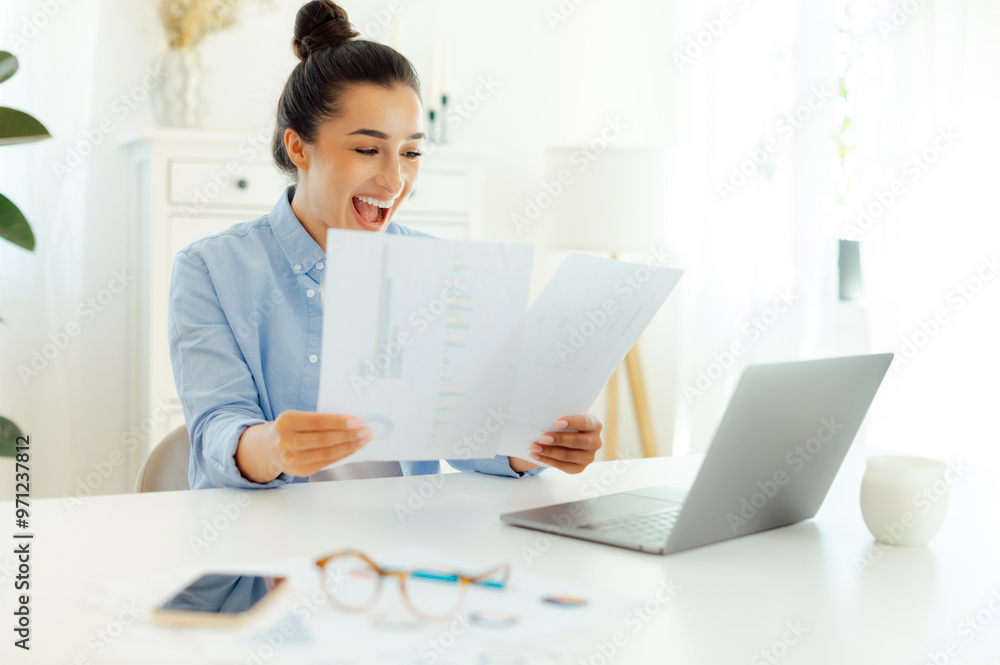 Happy joyful excited indian or arabian successful business woman sitting at a workplace, analyzing financial documents, rejoicing in success, good work results, smiling Happy joyful excited indian or arabian successful business woman sitting at a workplace, analyzing financial documents, rejoicing in success, good work results, smiling