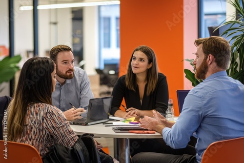 Collaborative Office Dynamics Young professionals engage in animated discussion, strategizing for business growth in a vibrant office setting. photo