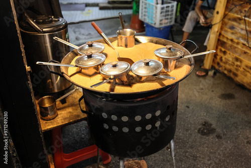 Coffee ban pot roasting on in a pan full of sand on flame at roadside café photo