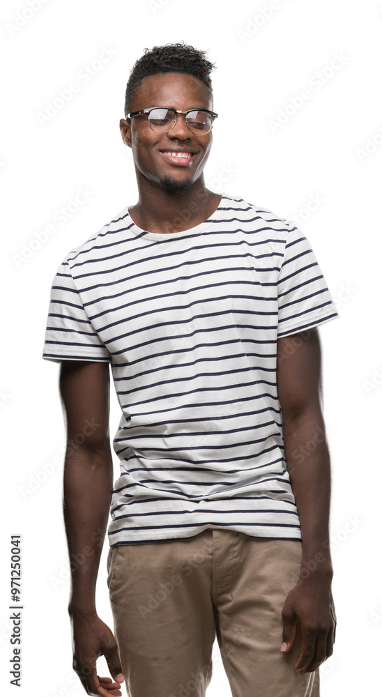 Young african american man wearing glasses and navy t-shirt looking away to side with smile on face, natural expression. Laughing confident. Young african american man wearing glasses and navy t-shirt looking away to side with smile on face, natural expression. Laughing confident.