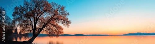 Stunning landscape view showcasing a tranquil lake at sunrise, highlighted by silhouettes of trees and distant mountains.