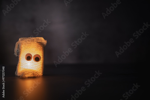 Obraz na plátně handmade halloween ghost with bandages and lit candle on dark background