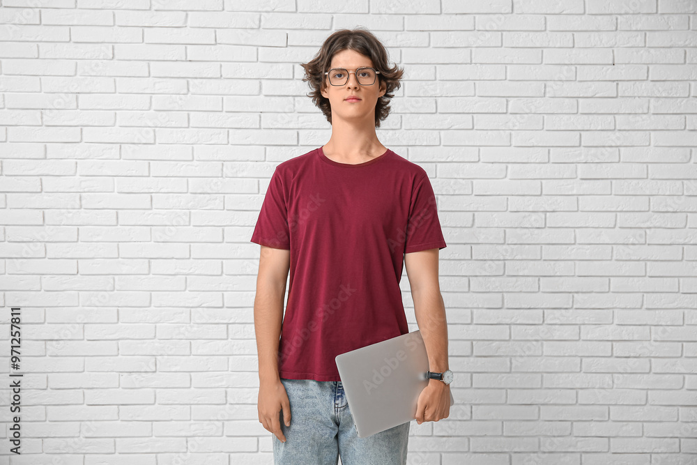 Male programmer in eyeglasses with laptop on white brick background Male programmer in eyeglasses with laptop on white brick background